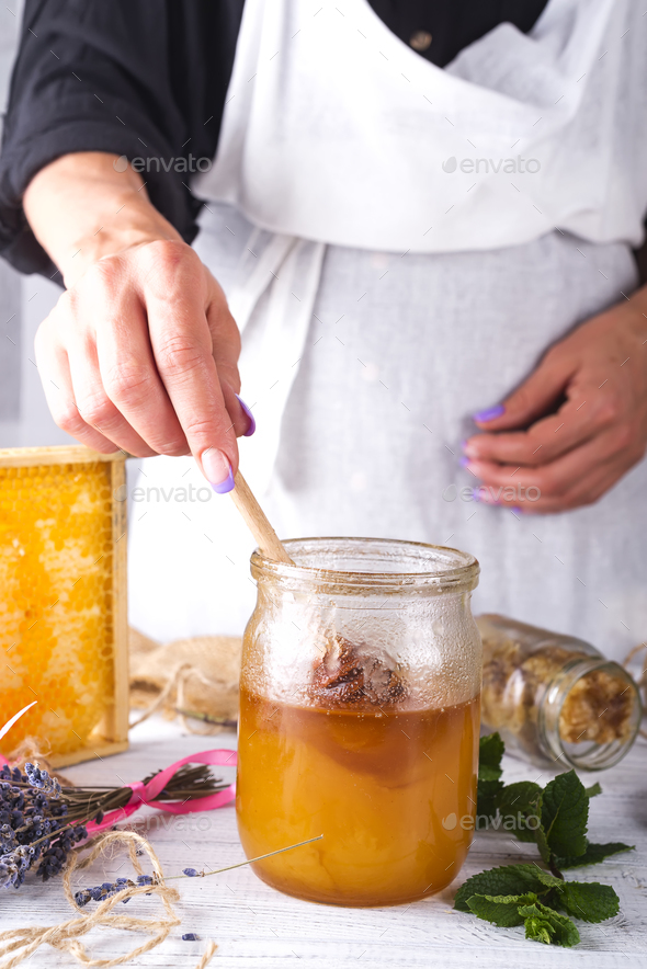 Hand with dipper picking honey from a jar of honey. - Stock Photo - Images
