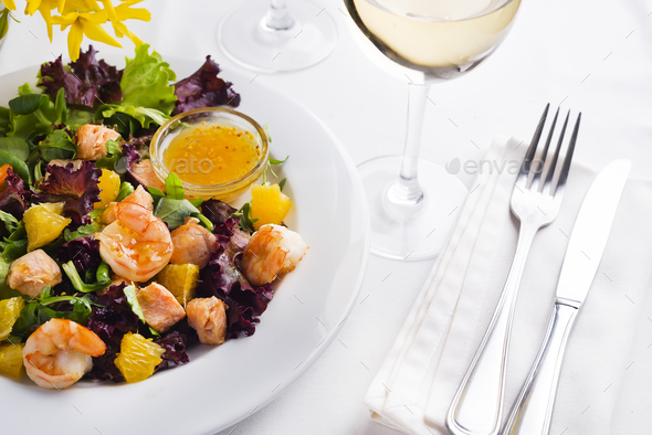 Tropical salad with prawns, lettuce, oranges and mango served on a plate with orange mustard sauce - Stock Photo - Images