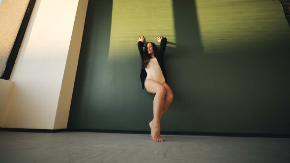 Brunette Young Women Poses, Slides on the Green Sunlight Wall. Sexy Long Legs.