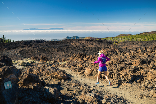 Young woman running in mountains on sunny summer day - Stock Photo - Images