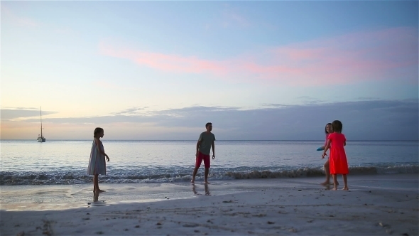 Happy Family of Four Playing Together on the Beach alt