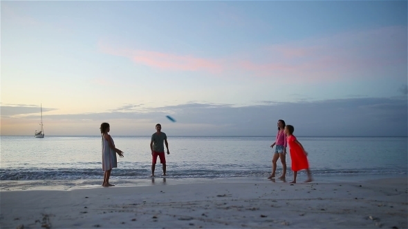 Happy Family Playing with Flying Disk at Beach at Sunset alt
