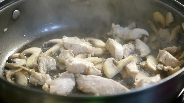 A Dainty Dish From Sliced Meat and White Mushrooms Is Mixed with a Spatula.