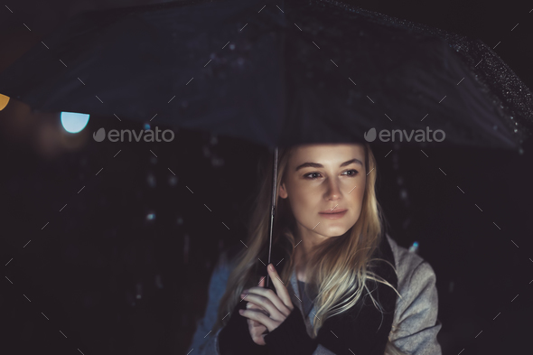 Thoughtful woman outdoors on rainy night - Stock Photo - Images