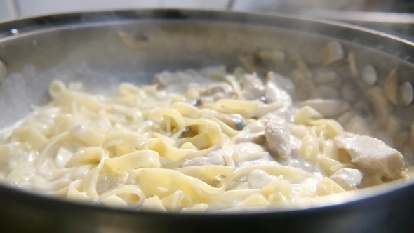 Macaroni Pasta and Mushrooms Are Fried on a Metallic Pan