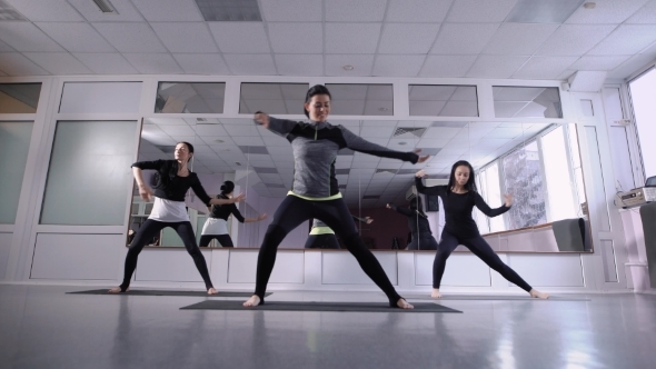 Female Trainer and Two Women Are Warming Up in a Training Hall with Mirror Wall, Pilates Complex for alt