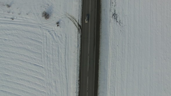 Car Overtaking Truck on a Winter Road Snowed Field