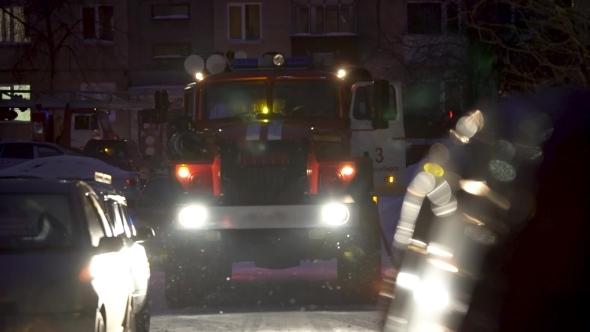 Fire Scene at Night with Fire Trucks and Flashing Lights on the Street. Unbranded Vehicles