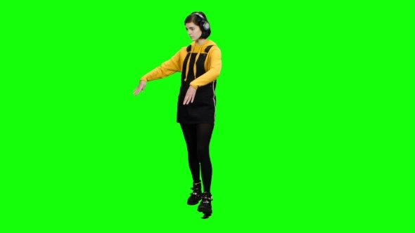 Teenage Girl Walks Down the Street Wearing Headphones and Makes a Different Move. Green Screen alt