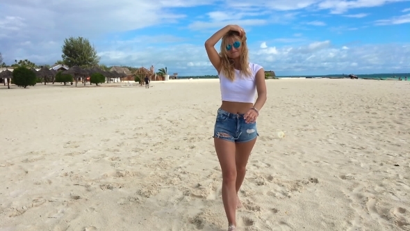 An Attractive Girl Walks Along the Beach and Flirts with the Camera. alt