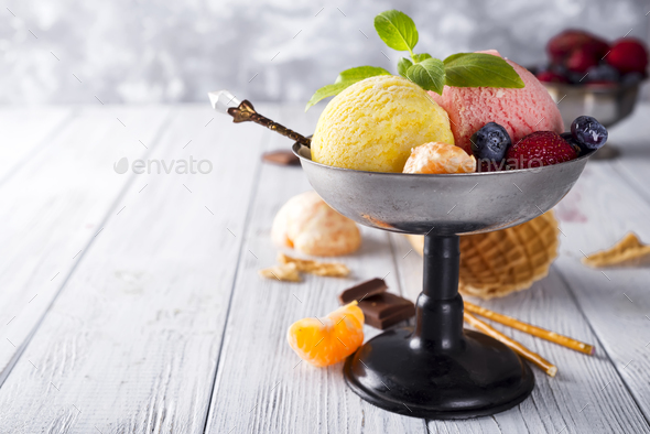 Bowl with ice cream with three different scoops of yellow, red colors and waffle cone, chocolate, - Stock Photo - Images