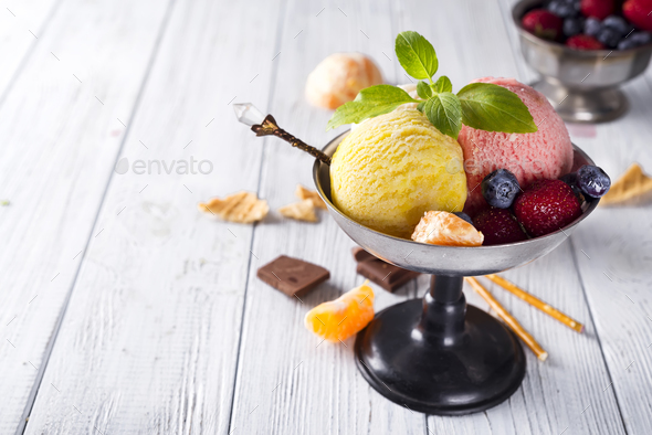 Bowl with ice cream with three different scoops of yellow, red colors and waffle cone, chocolate, - Stock Photo - Images