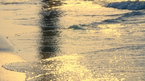 at Sunset, in the Rays of the Sun, the Surf. Waves Roll on the Sand and Spread Over It alt