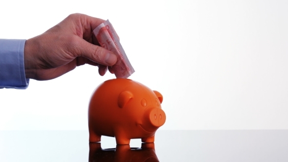 Male Hand Putting a Renminbi Bill in a Piggy Bank