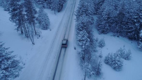 Silver Car Driving on Winter Country Road in Snowy Forest