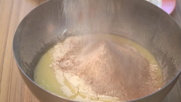 Sifting Cocoa Powder Into Bowl on Table on Wooden Background