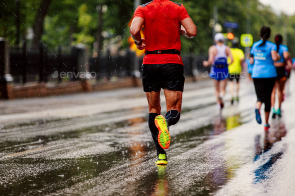 group of runners men and women running under rain drops city marathon Stock Photo by sportpoint74
