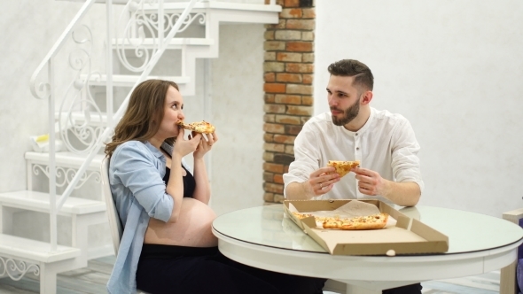Man and Pregnant Woman Eating Pizza at Home in Their