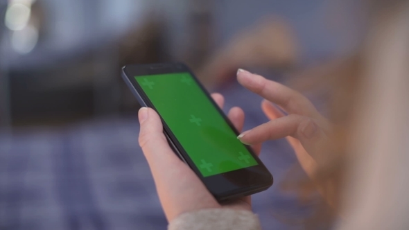 Woman Is Holding Smartphone with Green Screen in Home