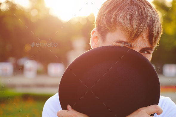 Beautiful woman hiding face behind hat showing eyes - Stock Photo - Images