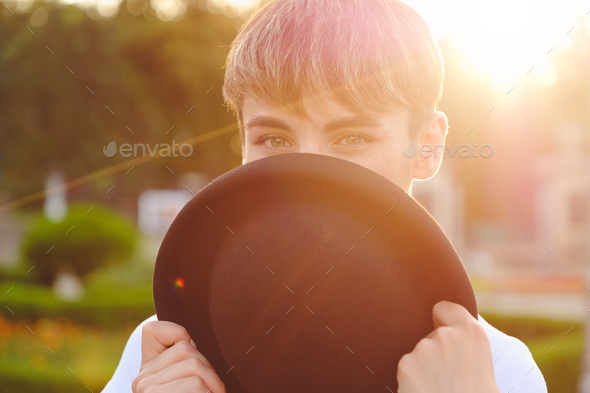 Beautiful woman hiding face behind hat showing eyes - Stock Photo - Images