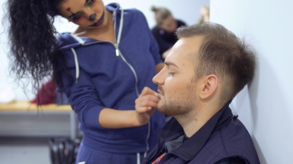 Woman with Horrible Greasepaint on Face Help Colleague and Makes Make-up for Him alt