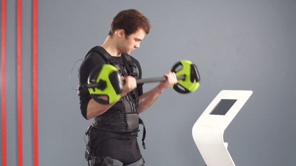 Fit Man Wearing Black Electrostimulation Suit Lifting Barbell. alt