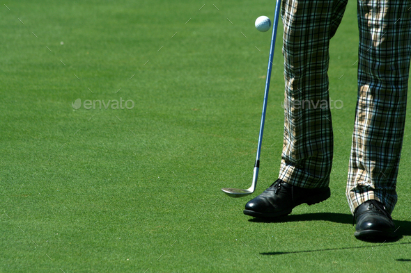 Golfer juggling a golf ball with retro pants - Stock Photo - Images