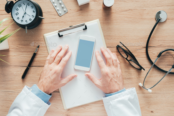 Doctor using smartphone app in hospital office - Stock Photo - Images