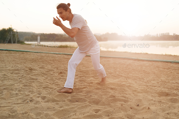 Athletic capoeira performer making movements on the beach - Stock Photo - Images