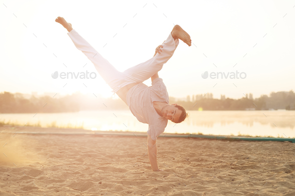 Athletic capoeira performer workout training on the beach sunris - Stock Photo - Images