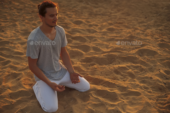 Shot of healthy young man standing in yoga pose on the sand. - Stock Photo - Images
