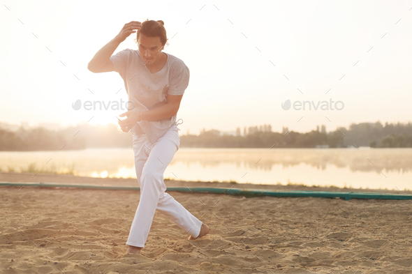 Athletic capoeira performer making movements on the beach - Stock Photo - Images