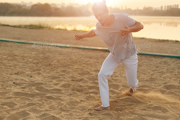 Athletic capoeira performer making movements on the beach - Stock Photo - Images