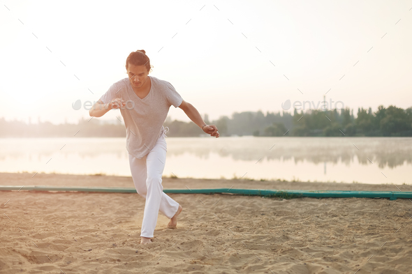 Athletic capoeira performer making movements on the beach - Stock Photo - Images
