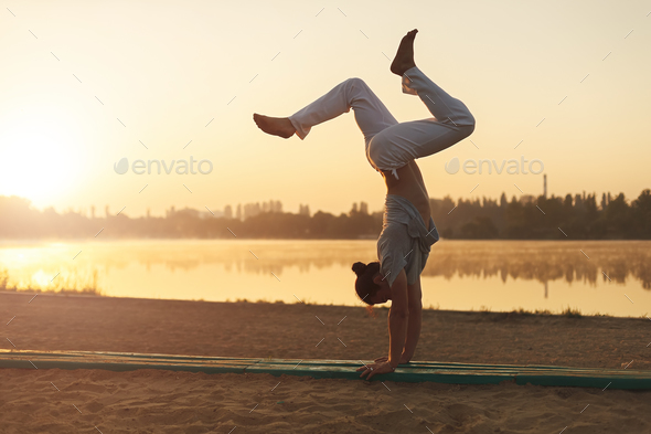 Athletic yoga man workout training on the beach sunrise - Stock Photo - Images