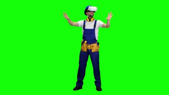 Worker in a Helmet and in Glasses of Virtual Reality on Green Screen alt