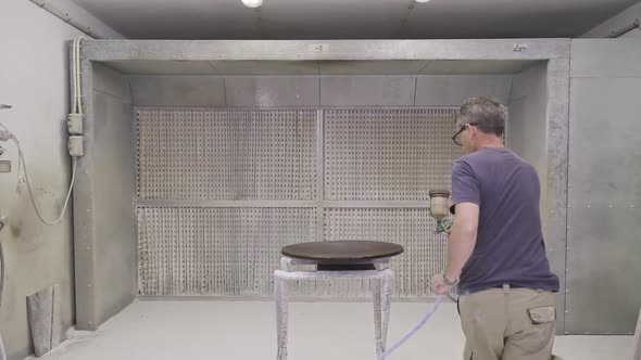 Workman using airbrush for applying flame retardant to wood detail ensuring fire protection alt