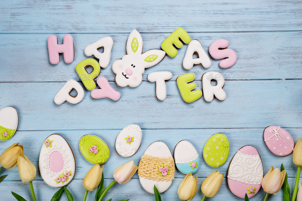 Easter cookies letter Happy Easter and colorful eggs with tulips on wood background - Stock Photo - Images