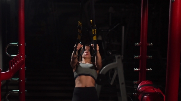 Young Fit Woman Doing Pull-ups on Gymnastic Rings. Muscular Young Female Athlete Exercising with alt