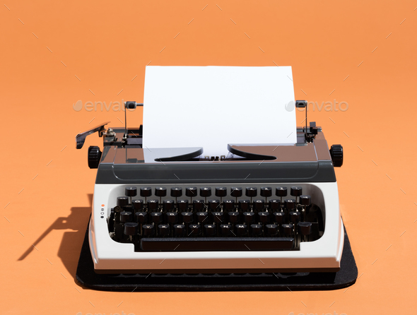 View of a vintage typewriter with a blank paper. Stock Photo by