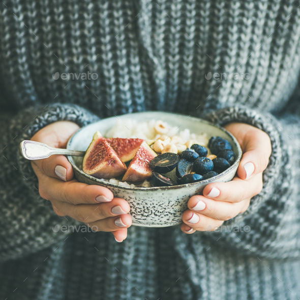 Woman in sweater holding bowl of rice porridge, square crop - Stock Photo - Images