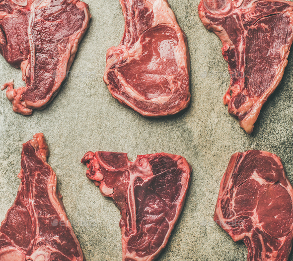 Flat-lay of fresh raw beef meat steaks, grey background - Stock Photo - Images