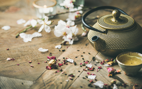 Iron teapot, cups, dried rose buds, blooming almond flowers, candles - Stock Photo - Images