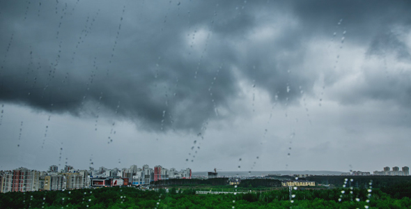 Rainy Clouds Sailing Above a City and Drops of Water on Window.