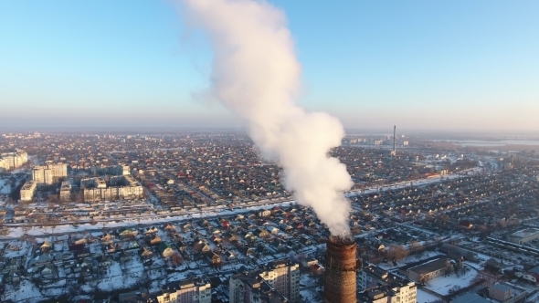 Aerial Shot of Giant Heating Chimney with White Smoke in Snowy City in Winter