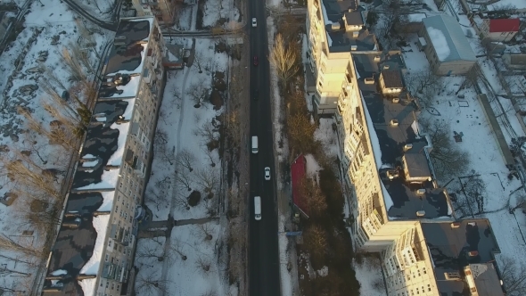 Aerial Shot a Snowy Street with Going Cars on It Between Multistireyed Buildings