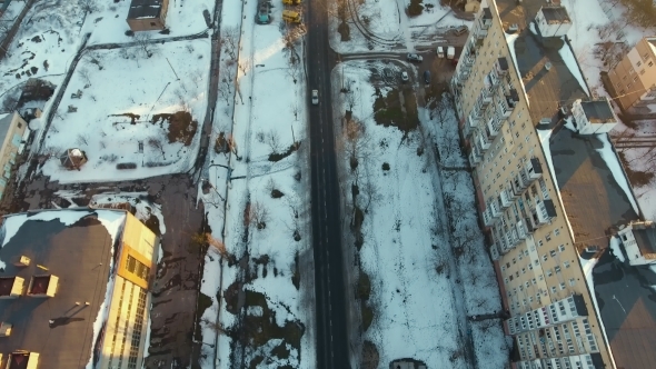 Aerial Shot a Snowy Street with Moving Cars on It Among Multistireyed Buildings