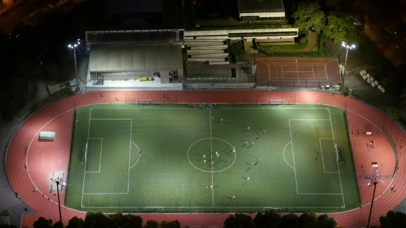 Aerial Shot of Modern Football Field with Playing Athletes in Paris at Night