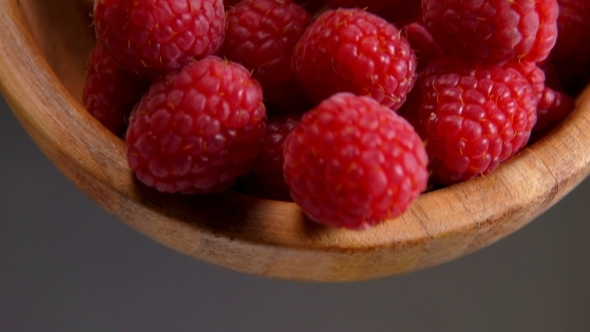 Ripe Red Raspberries Are Poured From a Bamboo Bowl alt